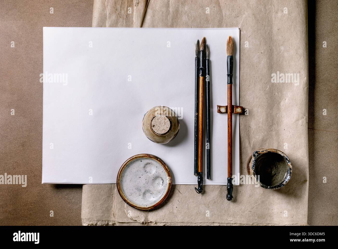 Outils traditionnels de calligraphie chinoise sur papier blanc. Brosses pierre d'encre et récipient d'encre disposés sur fond de papier de riz artisanal et de mûrier. Artiste Banque D'Images