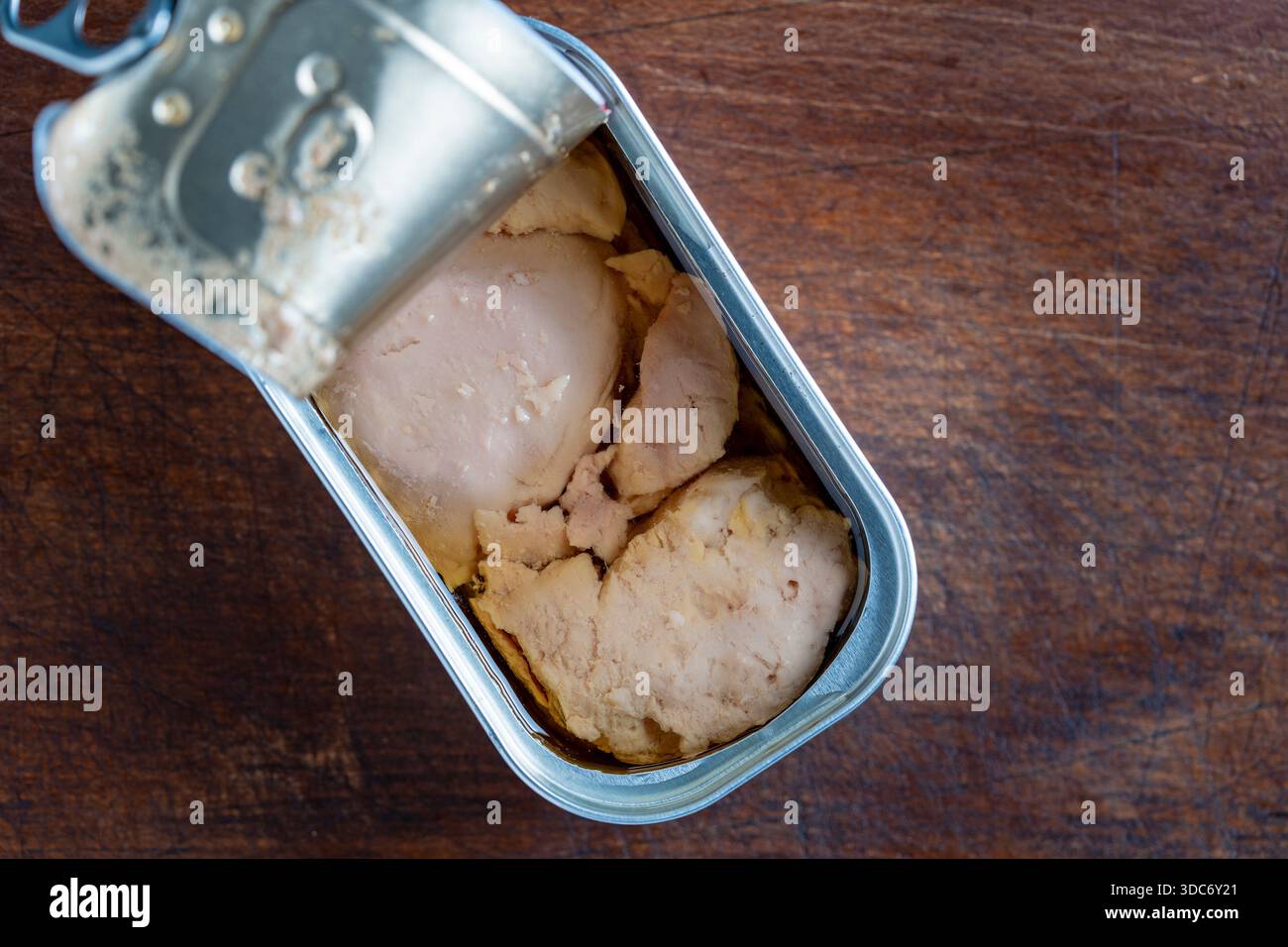 Boîte de conserve ouverte avec foie de morue sur fond de table en bois, gros plan, vue de dessus, espace de copie Banque D'Images