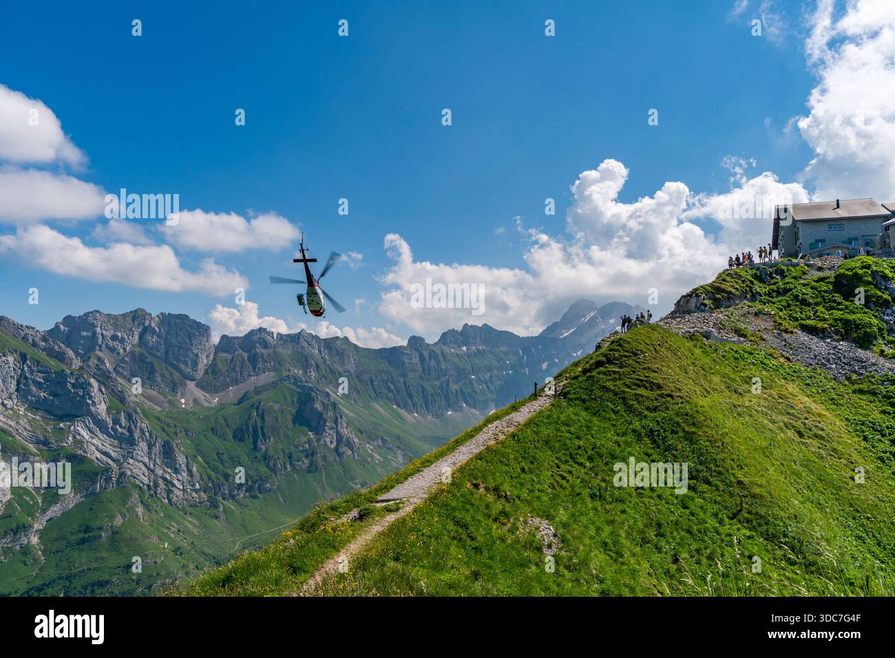 Un moment spectaculaire capture la mission de sauvetage en hélicoptère au-dessus des randonneurs en profitant de vues panoramiques sur les Alpes sous un ciel lumineux Banque D'Images