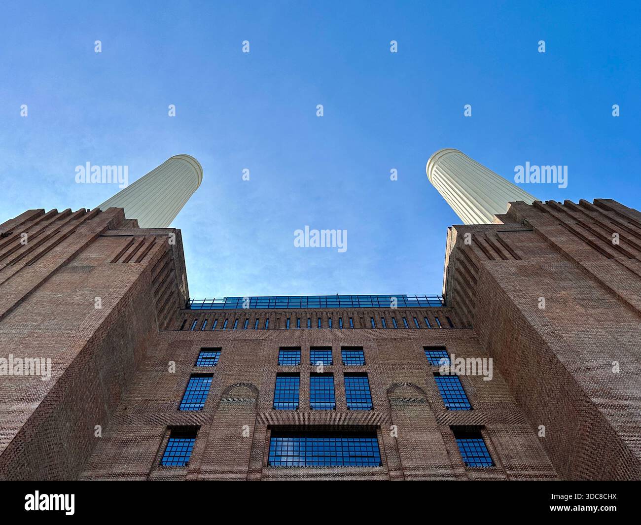 Battersea Power Station, Londres — imposantes cheminées et briques industrielles s'élevant dans un ciel bleu clair à cet emblématique monument Art déco. Banque D'Images