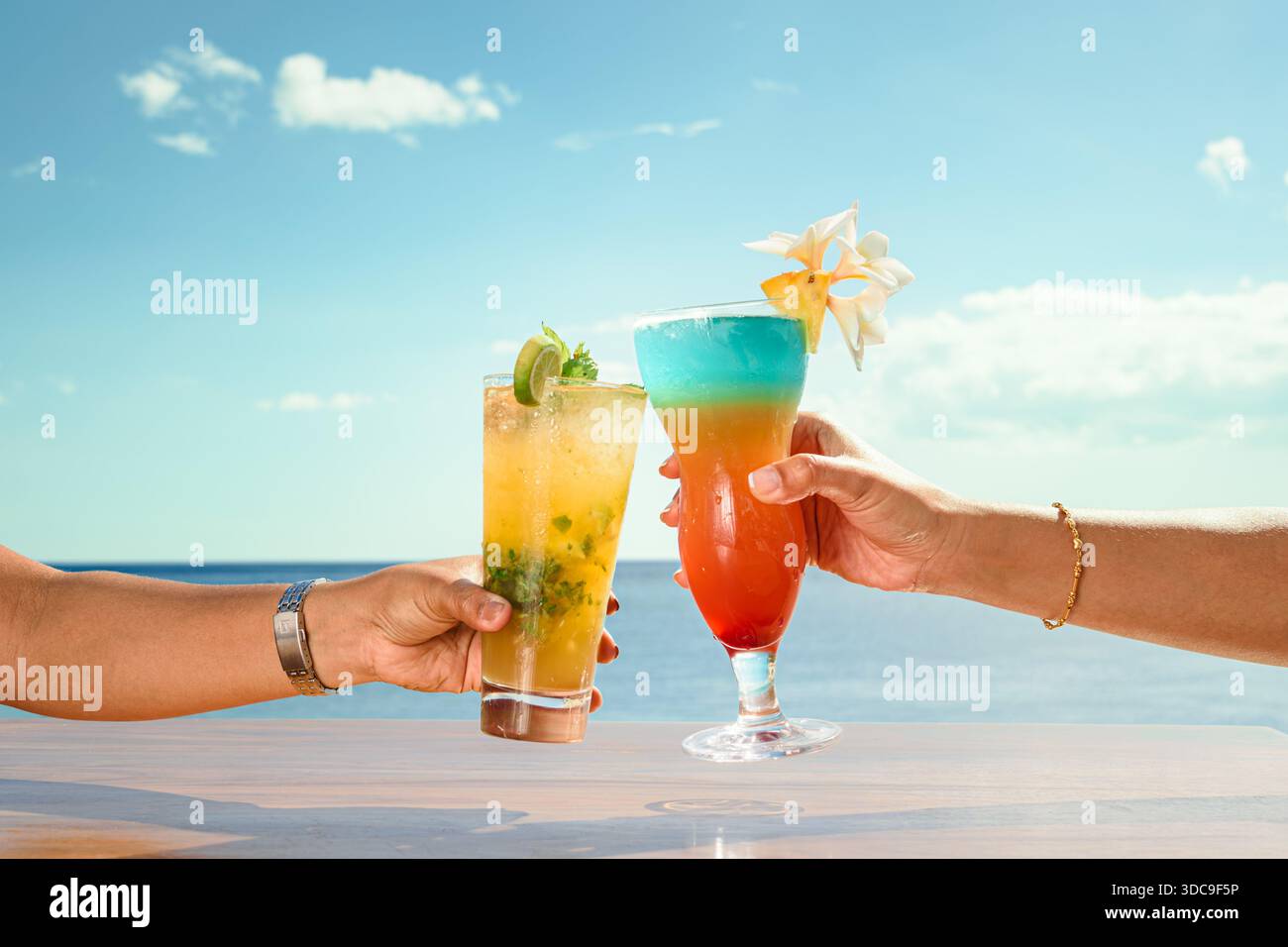 Célébrez la vie insulaire ! Des cocktails vibrants sont dressés dans un toast joyeux sur fond d'océan turquoise. Une escapade tropicale idyllique rayonne de détente. Banque D'Images