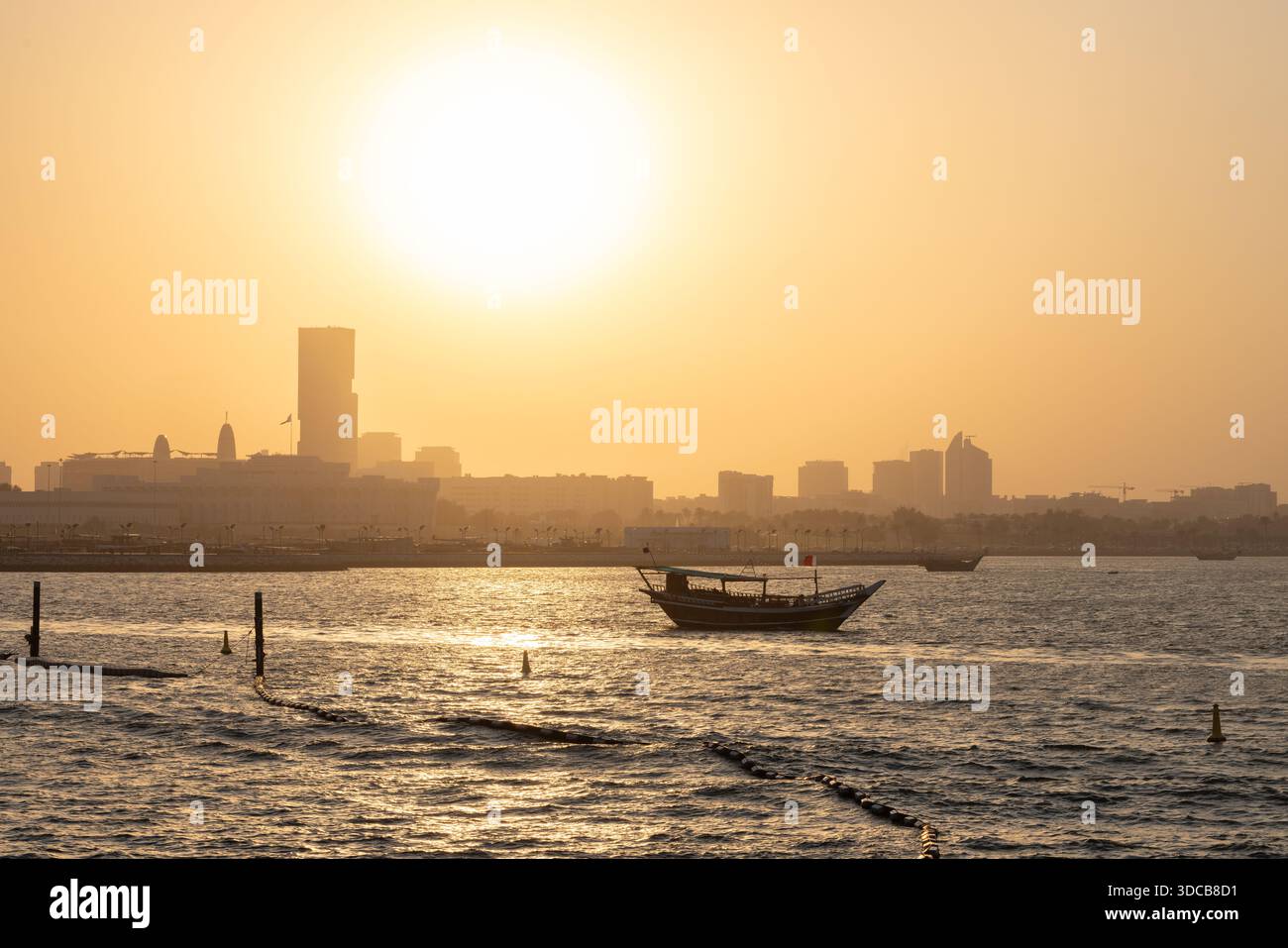 Croisière en boutre au coucher du soleil le long du port de Doha Corniche, avec bateaux traditionnels et vue sur les toits Banque D'Images