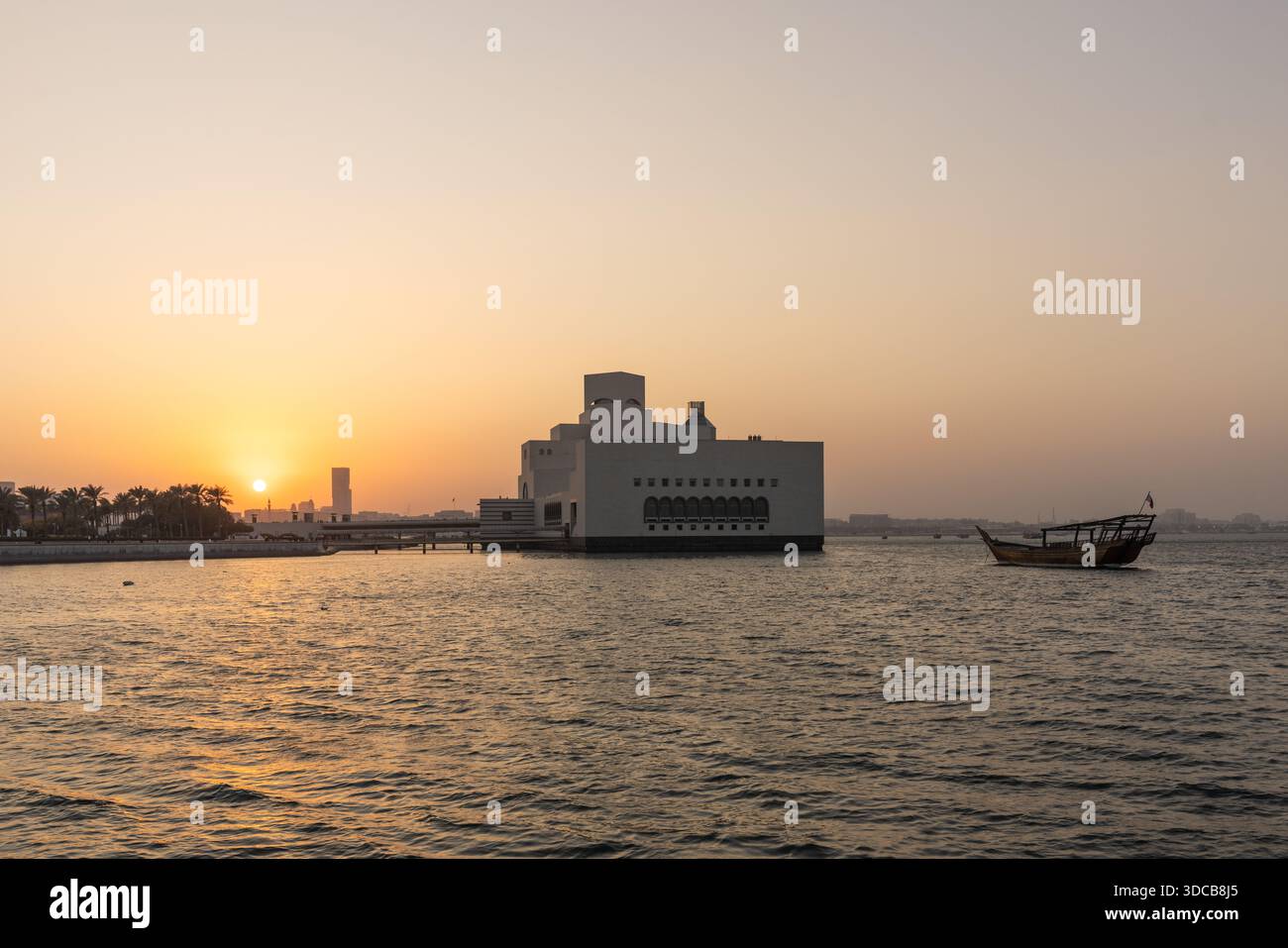 Croisière en boutre au coucher du soleil le long du port de Doha Corniche, avec bateaux traditionnels et vue sur les toits Banque D'Images