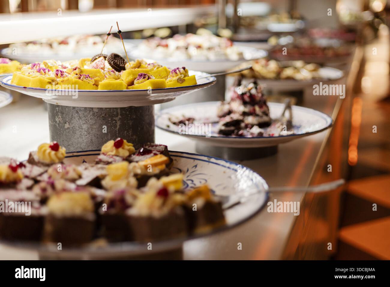 Les assiettes sont remplies de différents types de gâteaux et de pâtisseries disposés sur une table. Les clients peuvent choisir parmi une variété de bonbons lors de cet événement buffet à t Banque D'Images