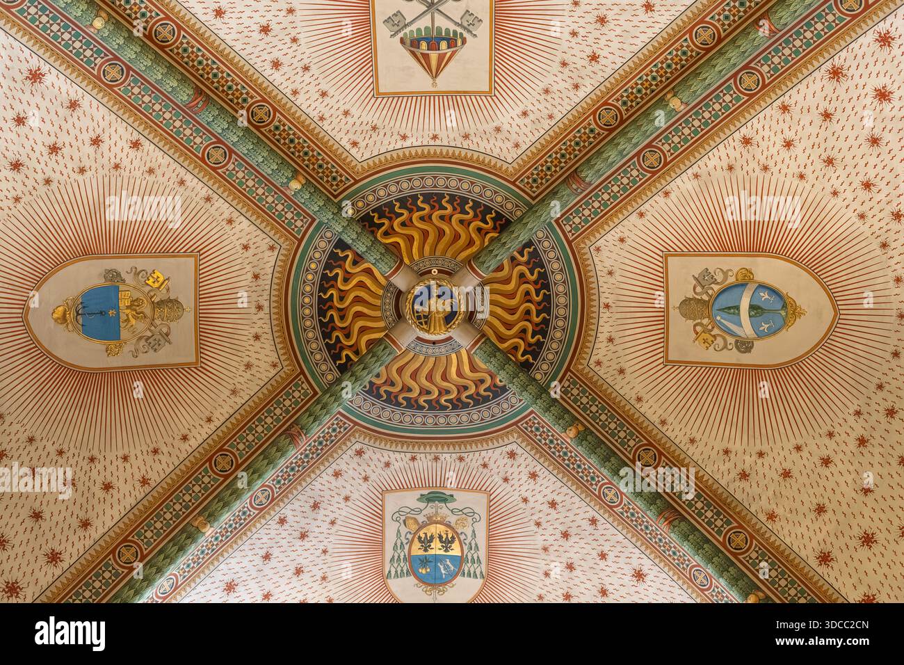 Plafond architectural décoratif orné d'un motif solaire central, de quatre poutres croisées et d'emblèmes héraldiques. Couleurs riches, motifs complexes, et Banque D'Images