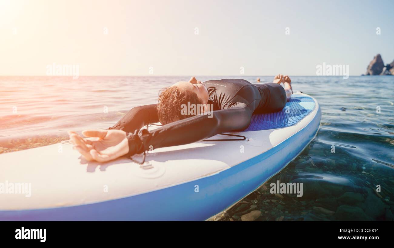 Paddleboard Yoga Ocean Man pratique le yoga pose sur Paddleboard à Ocean at Sunset Banque D'Images
