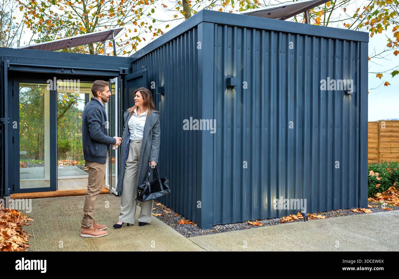 Couple heureux parlant à l'extérieur d'un immeuble de bureaux de coworking modulaire fait avec des conteneurs d'expédition Banque D'Images