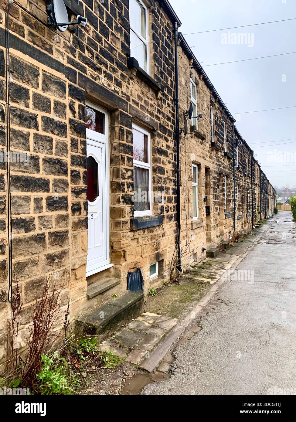 Maisons mitoyennes traditionnelles construites en pierre sur une rue assez résidentielle dans le Yorkshire en Angleterre un jour couvert après les précipitations - Image de stock capturée avec un smartphone