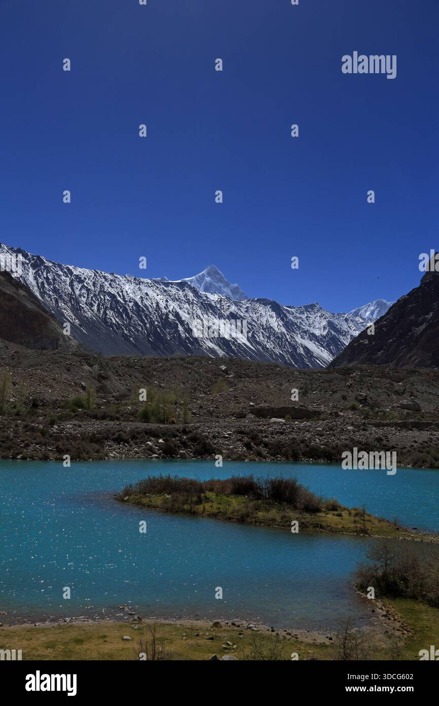 Vue sur un lac turquoise reflétant les montagnes enneigées sous un ciel bleu vibrant, un paysage serein de grandeur nature, passu, Gilgit Baltist Banque D'Images