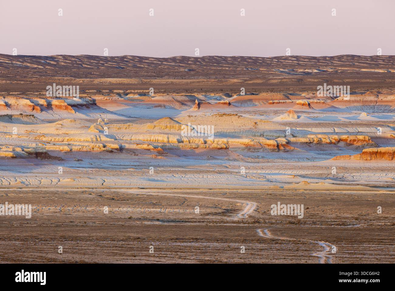 Vue du soleil peignant le paysage aride avec des teintes douces, éclairant le terrain accidenté dans la lumière dorée, Senek, région de Mangystau, Kazakhstan. Banque D'Images