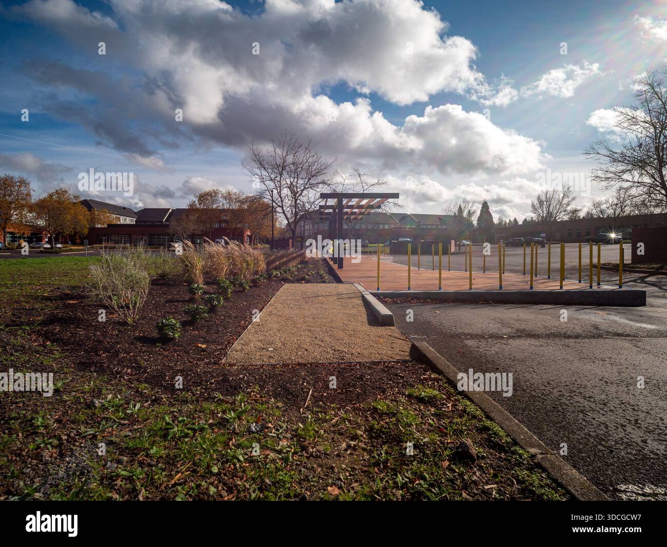 Vue d'un sentier doré menant à une structure de jeu sous un ciel vivant avec des nuages dynamiques, contrastant avec l'asphalte sombre et humide, Apollo Park, Banque D'Images