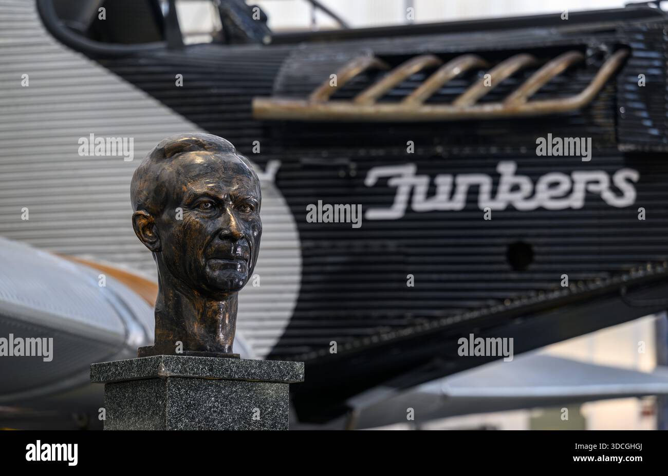 PRODUCTION - 18 décembre 2025, Saxe-Anhalt, Dessau-Roßlau : un buste portrait du concepteur d'avions Hugo Junkers se tient devant un Junkers F13 dans le Musée de technologie 'Hugo Junkers' de Dessau-Roßlau. Le musée se concentre sur le travail du concepteur d'avions et entrepreneur Hugo Junkers, de la technologie des appareils de chauffage et de gaz à l'ingénierie des moteurs et de la mécanique et à l'aviation. L'exposition centrale est un Junkers Ju restauré 52/3m. Une autre partie de l'exposition est consacrée à la construction aéronautique en RDA entre 1954 et 1961. Photo : Hendrik Schmidt/dpa Banque D'Images
