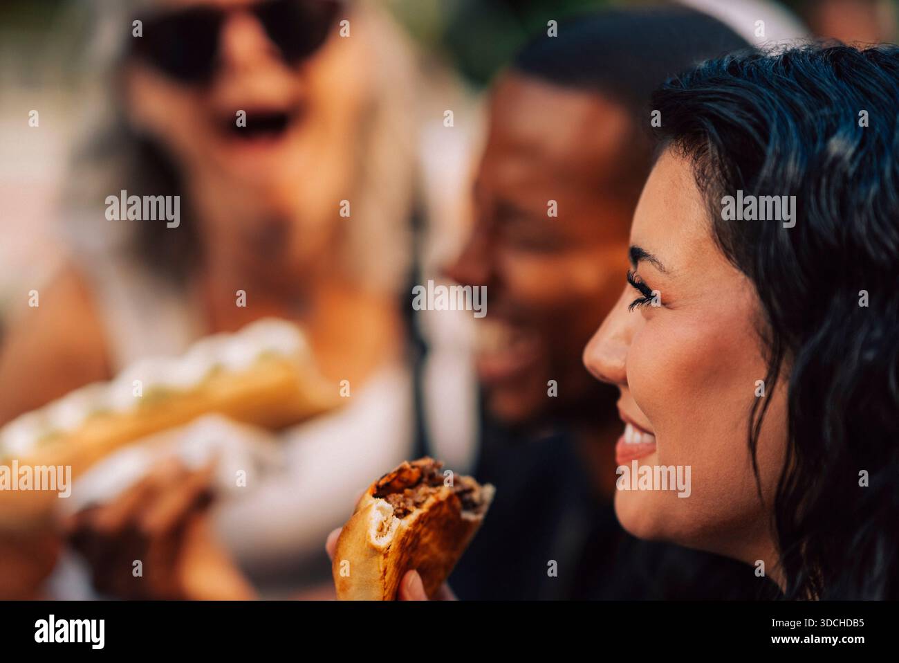 Jeune femme souriante mangeant de l'apéritif avec des amis Banque D'Images