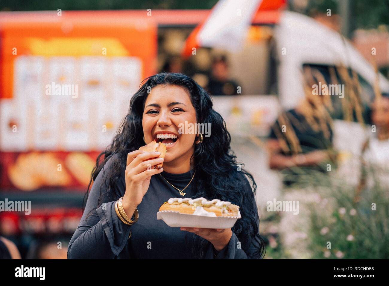 Portrait d'une jeune femme heureuse mangeant du hot dog Banque D'Images