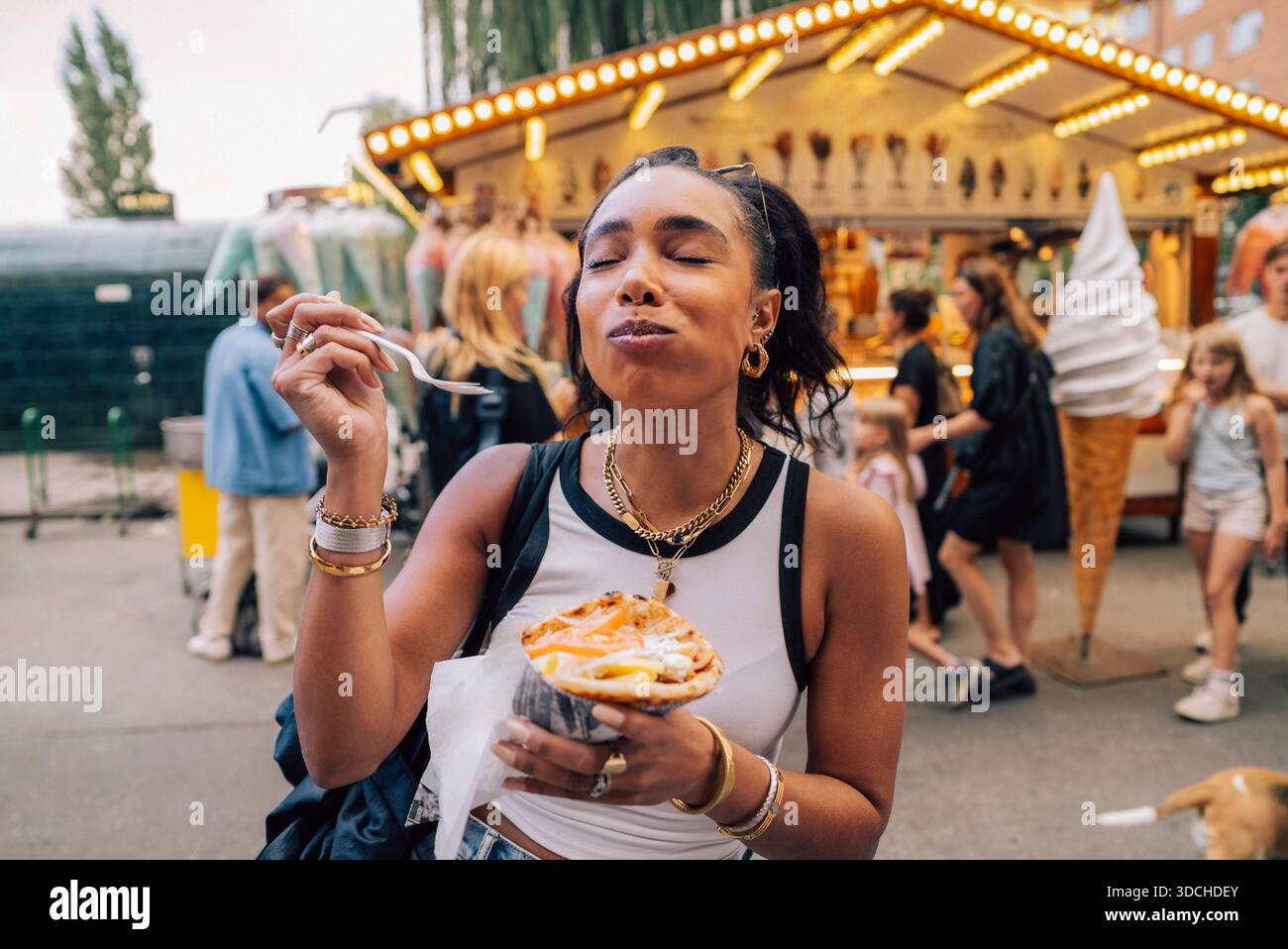 Femme satisfaite mangeant des frites à la fête de rue Banque D'Images