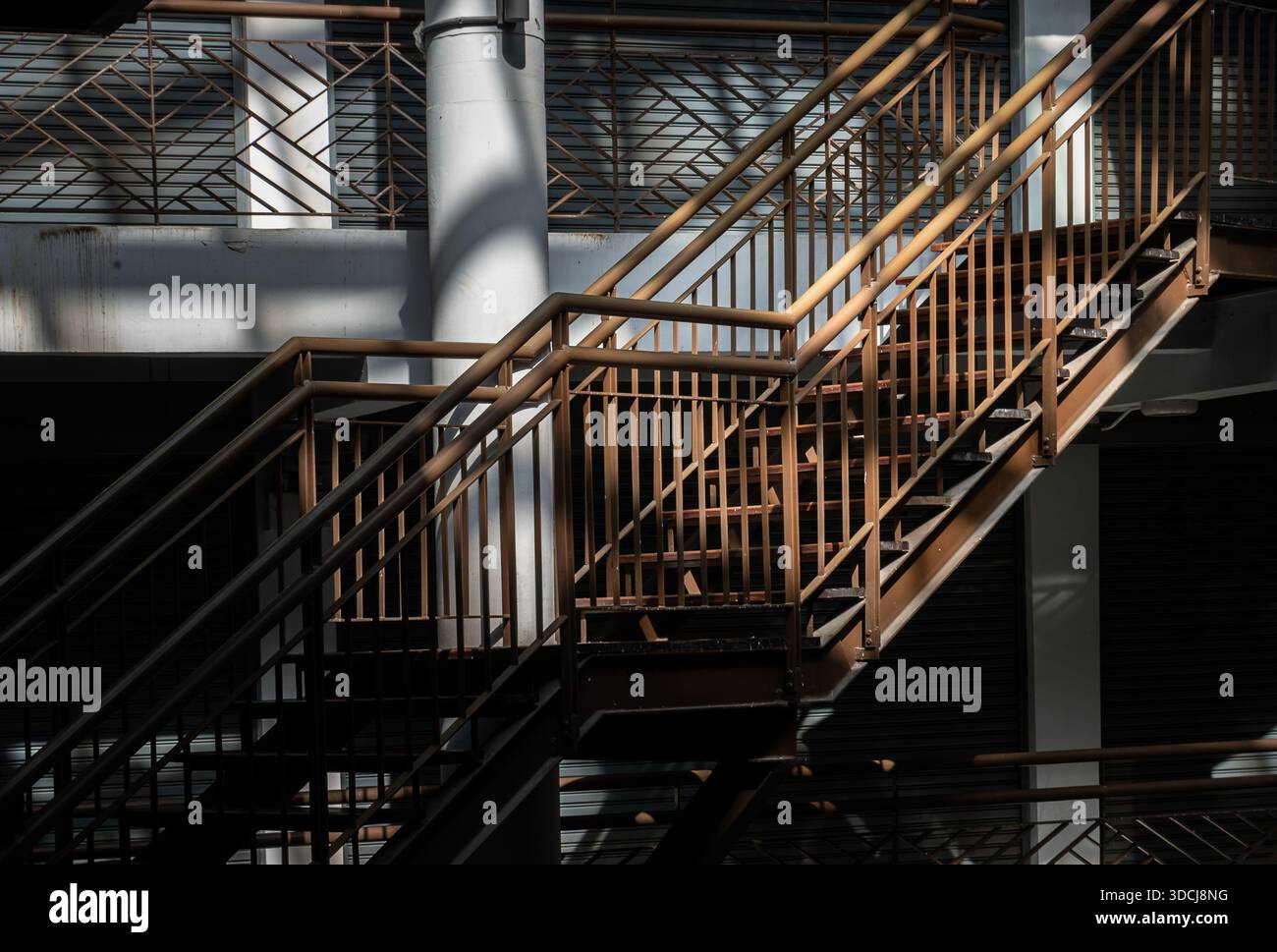 Bangkok, Thaïlande - 29 octobre 2025 - Un escalier métallique de style industriel de premier plan monte à travers un environnement très contrasté, illuminé de façon spectaculaire Banque D'Images