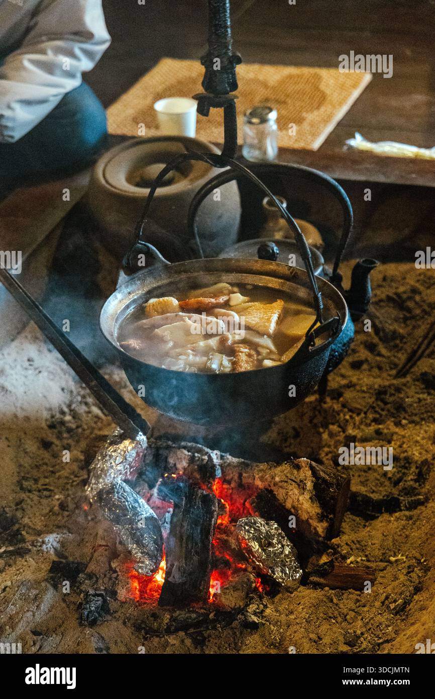 Les habitants cuisinent un repas japonais dans un irori traditionnel (foyer encastré) à Ichikokutochi Tateba Chaya le long du sentier Nakasendo, Nagano, Japon Banque D'Images