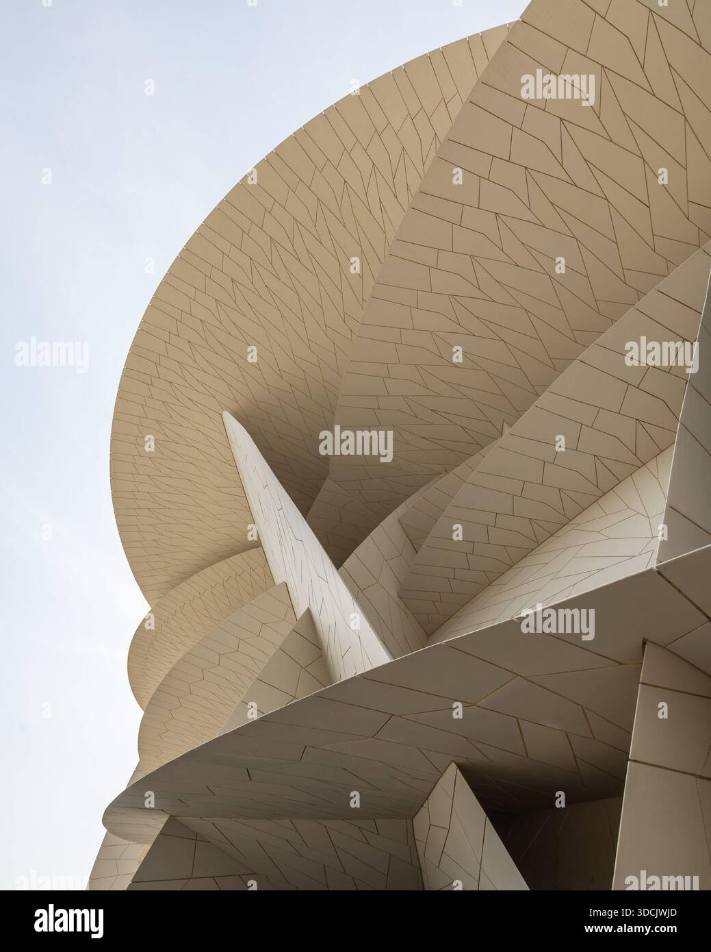 Vue de la structure unique en forme de pétales du Musée national du Qatar, avec ses teintes beiges contrastant avec le ciel dégagé, Doha, Qatar. Banque D'Images