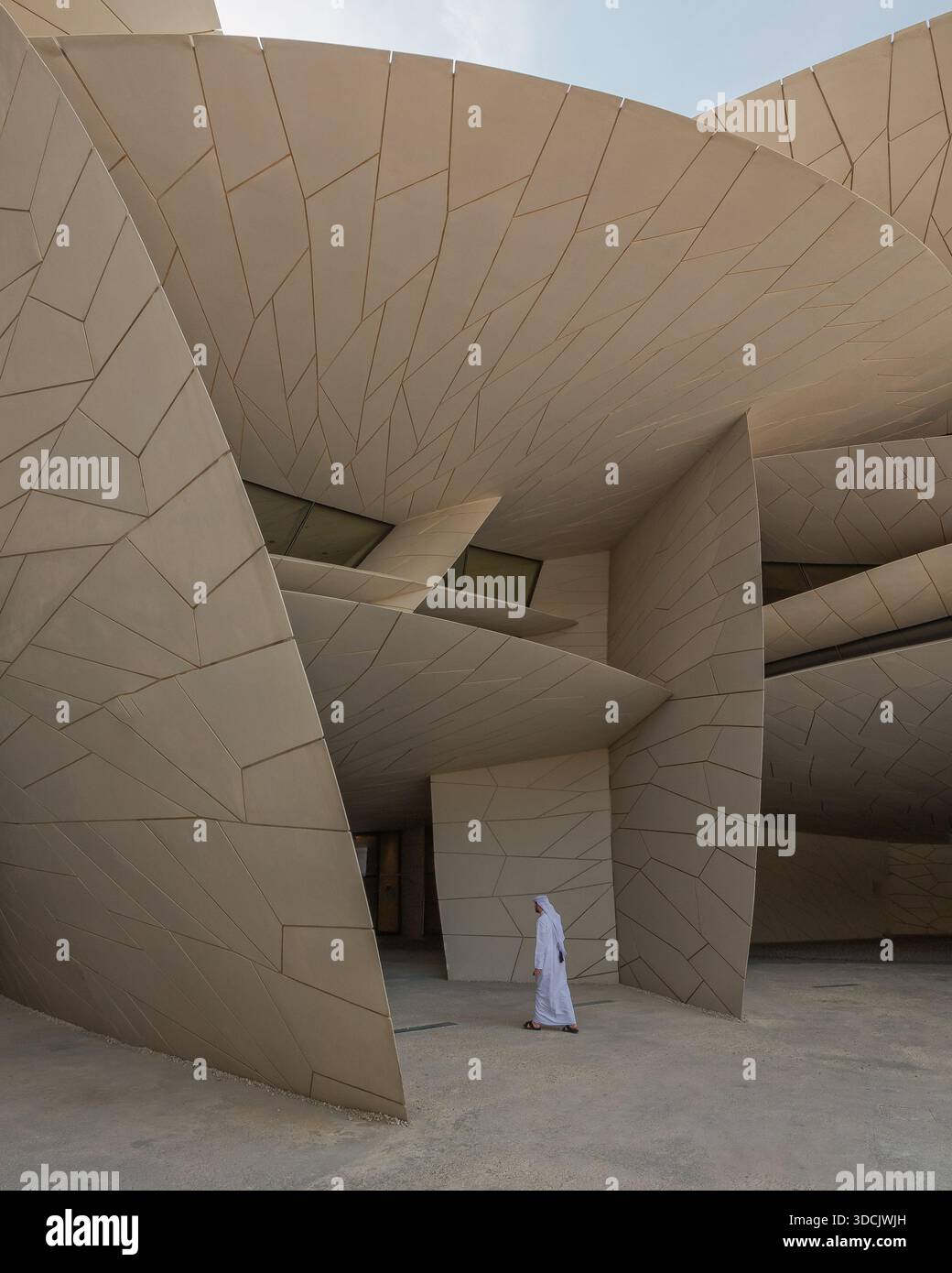 Vue de la façade beige en pétales du Musée national du Qatar, un homme en vêtements blancs traditionnels passe par, Doha, Qatar. Banque D'Images