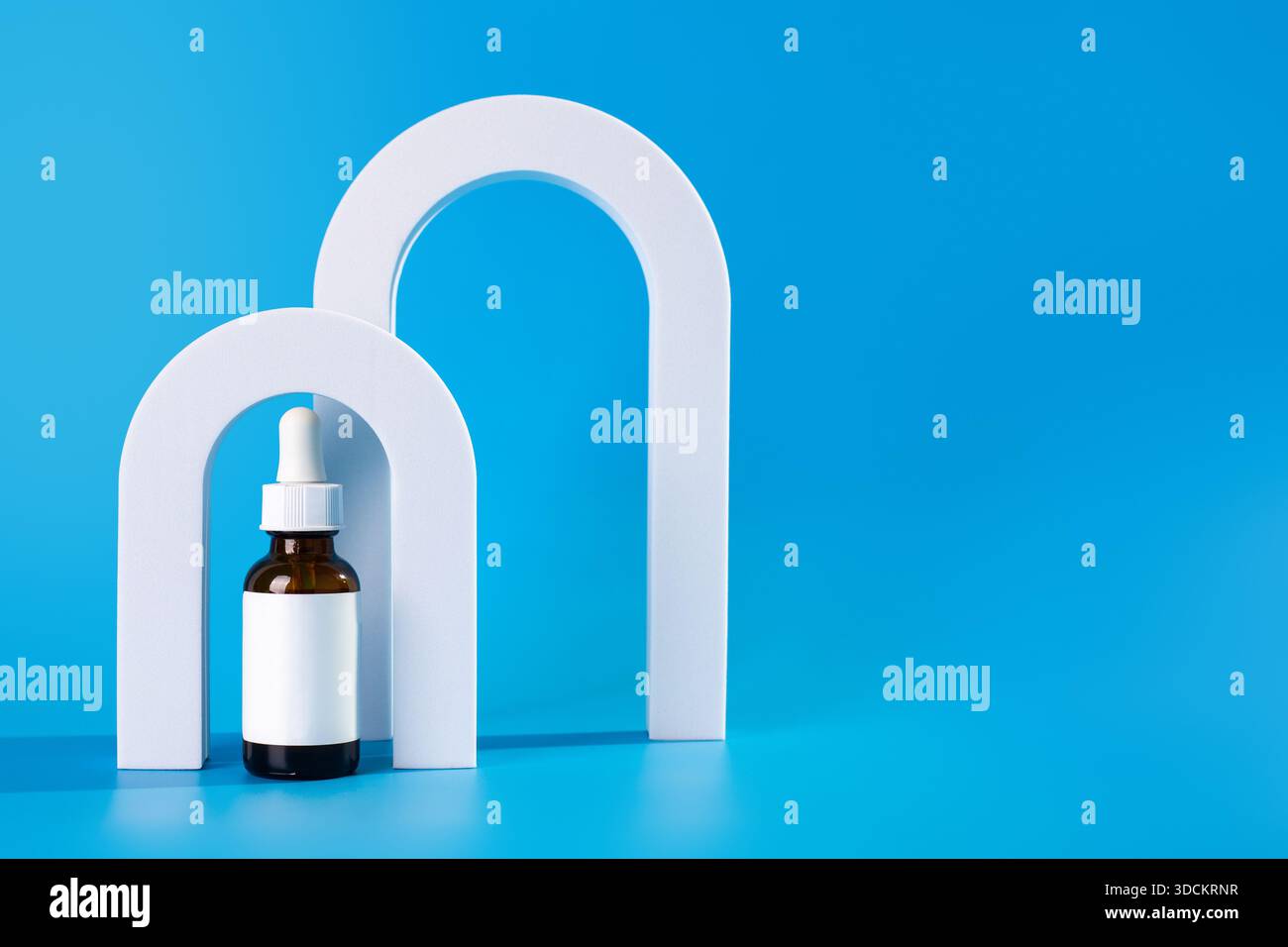 Sérum ou huile en flacon marron pour soins de la peau du visage. Produit de soin cosmétique dans un abat-jour en verre sur le fond bleu des arches. Copier l'espace. Banque D'Images