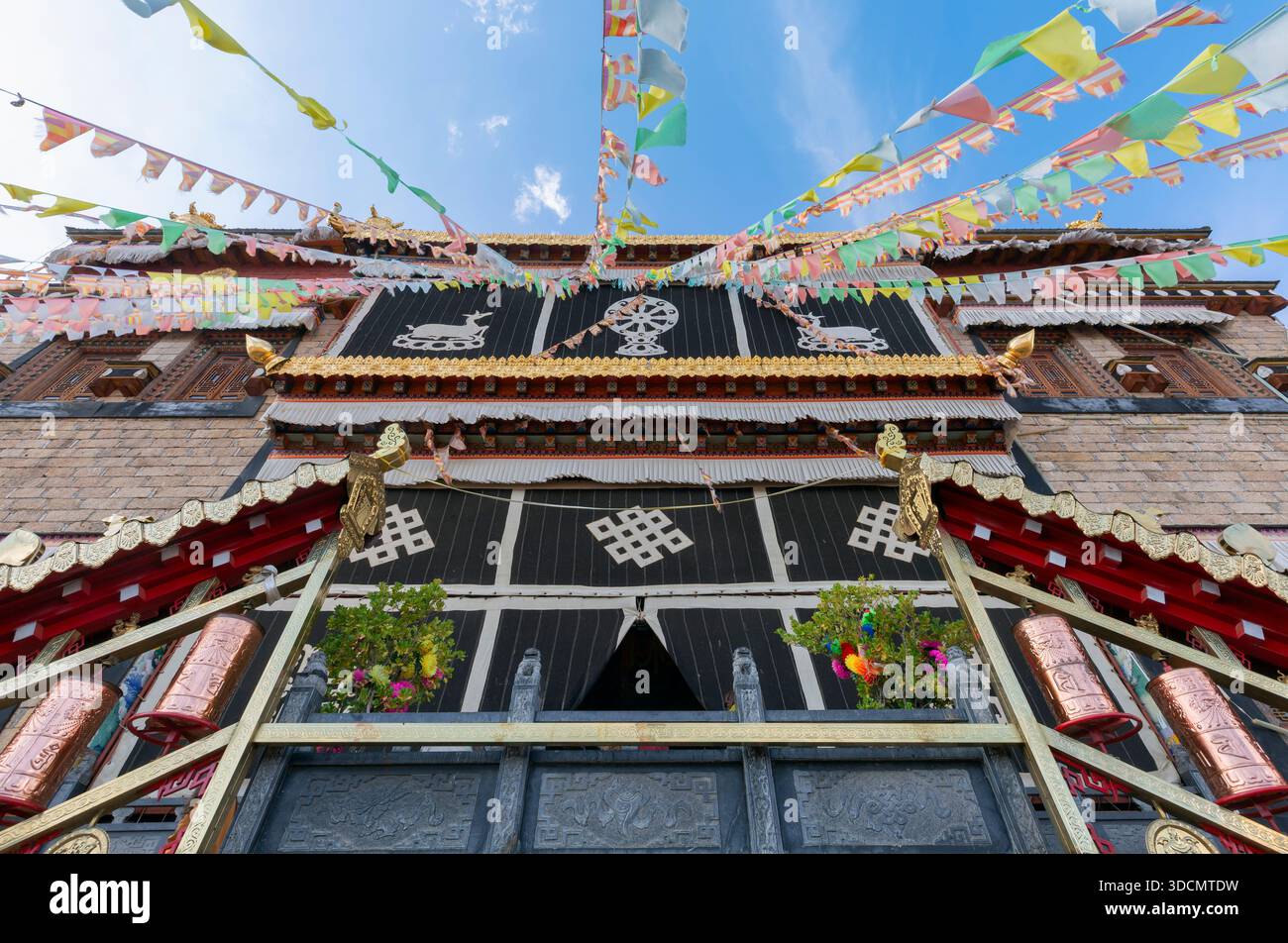 Architecture du monastère de Songzanlin avec des drapeaux de prière colorés flottant contre un ciel bleu clair. Banque D'Images