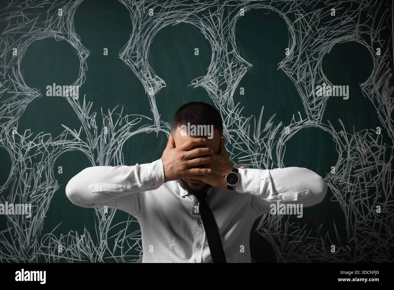 Homme d'affaires déprimé près des têtes dessinées sur le tableau. Semaine internationale de sensibilisation au stress Banque D'Images