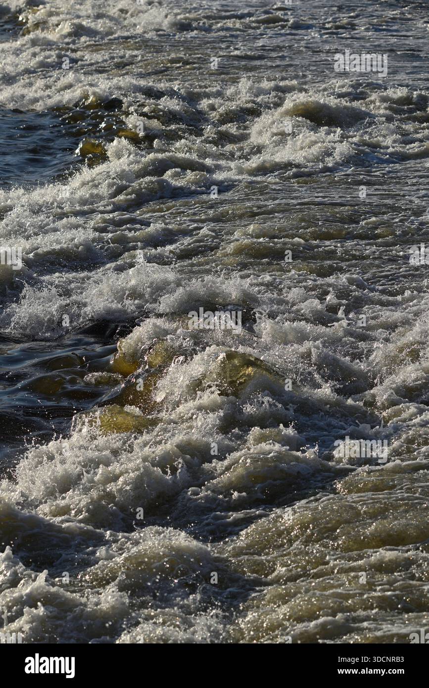 Gros plan des vagues océaniques qui s'écrasent sur les rochers, créant de la mousse blanche. Banque D'Images