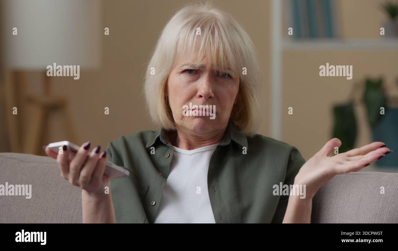 Frustré dame senior en colère vieille femme caucasienne avec le téléphone portable lisant de mauvaises nouvelles échec perdre la colère parler en regardant la caméra femme retraitée avec Banque D'Images