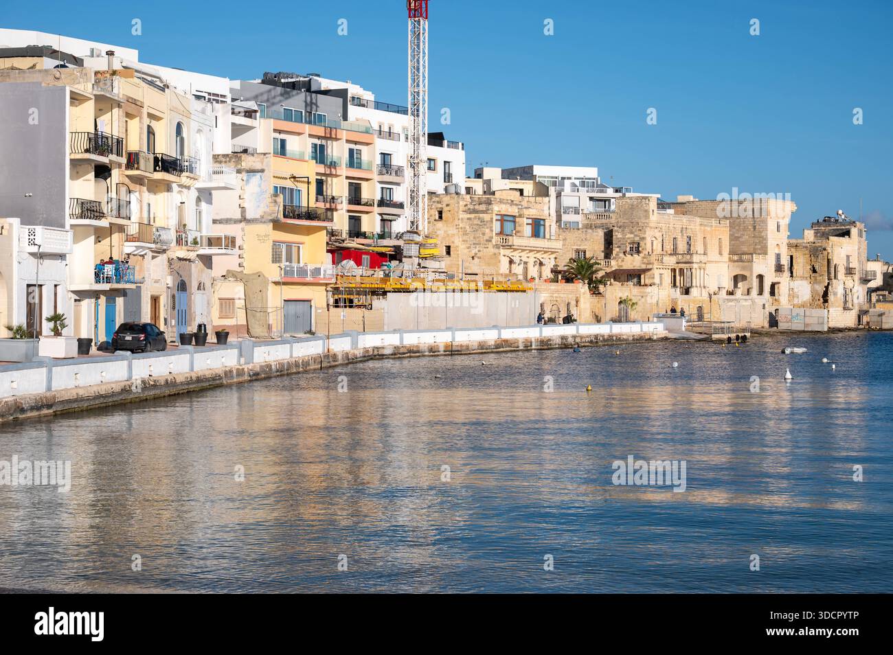 Petits bateaux colorés le long de la côte de BirÅ¼ebbuÄa à St Georges Bay sous un ciel bleu vif et la mer, créant une atmosphère de vacances méditerranéenne détendue BirÅ¼ebbuÄa, Malte, 8 décembre 2025. Banque D'Images