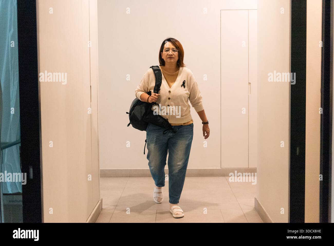 Femme marchant, portant sac à dos et ruban noir, symbolisant le deuil Banque D'Images