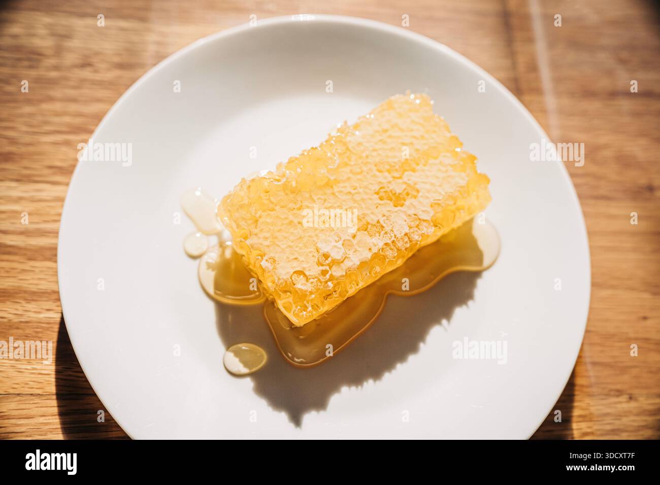 Nid d'abeille frais dégouttant miel cru sur l'assiette Banque D'Images