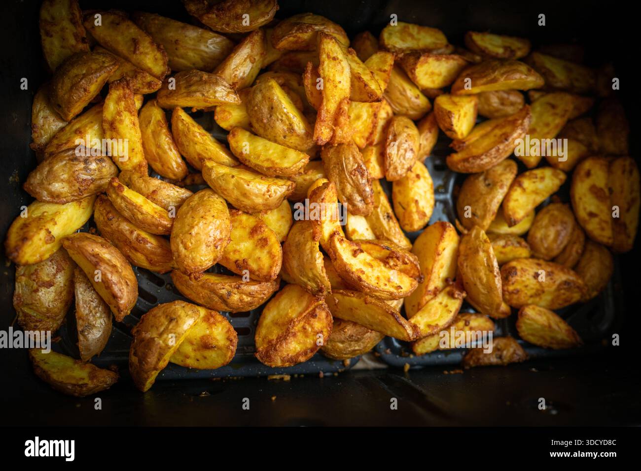 Photographie culinaire de haute qualité mettant en vedette des quartiers de pommes de terre croustillantes dorées fraîchement cuites dans un plateau de four. Gros plan, perspective descendante Banque D'Images