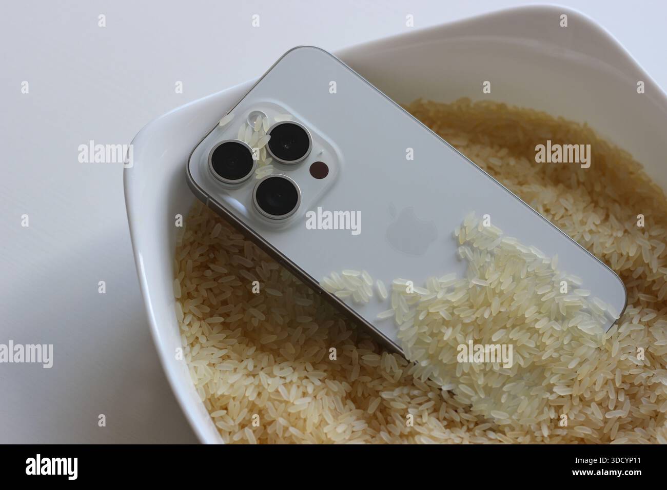 Smartphone recouvert de grains de riz non cuits après un dégât accidentel de l'eau Banque D'Images