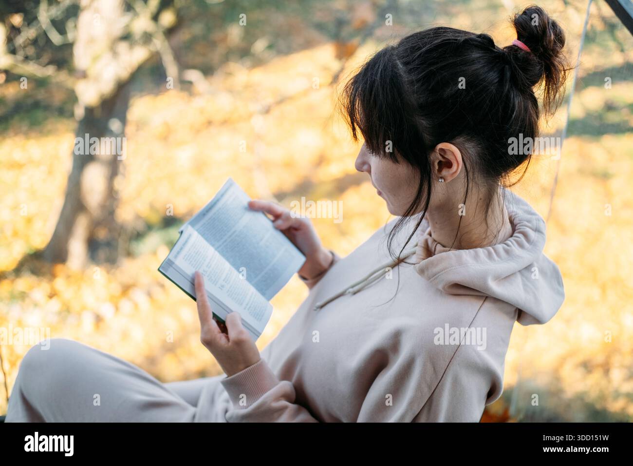 La jeune femme lit un livre en étant assise sur le balcon. Bien-être intellectuel, apprentissage tout au long de la vie, lecture attentive, vie lente. Banque D'Images