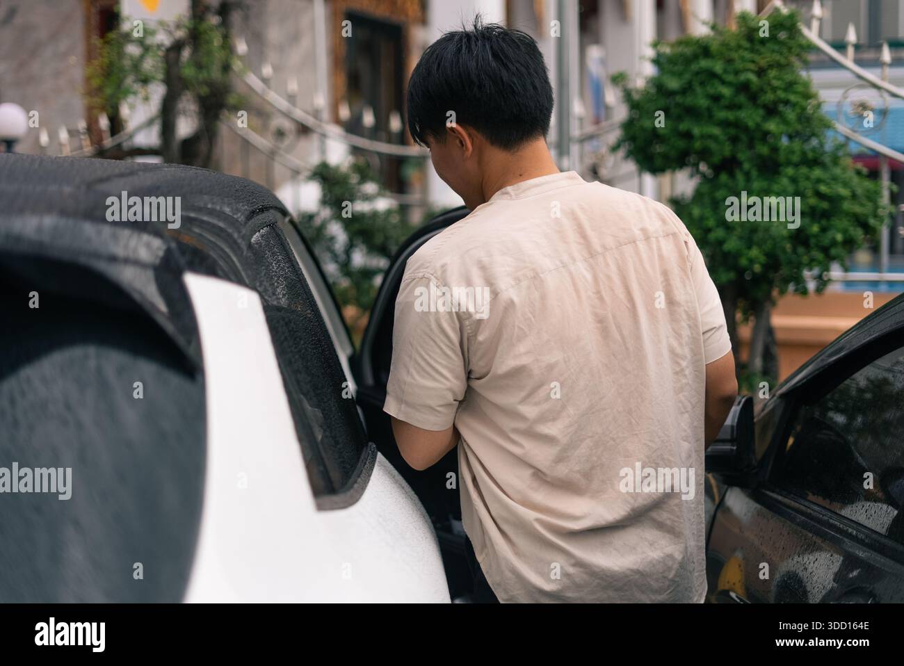 Homme entrant dans une voiture par temps pluvieux d'une vue arrière Banque D'Images