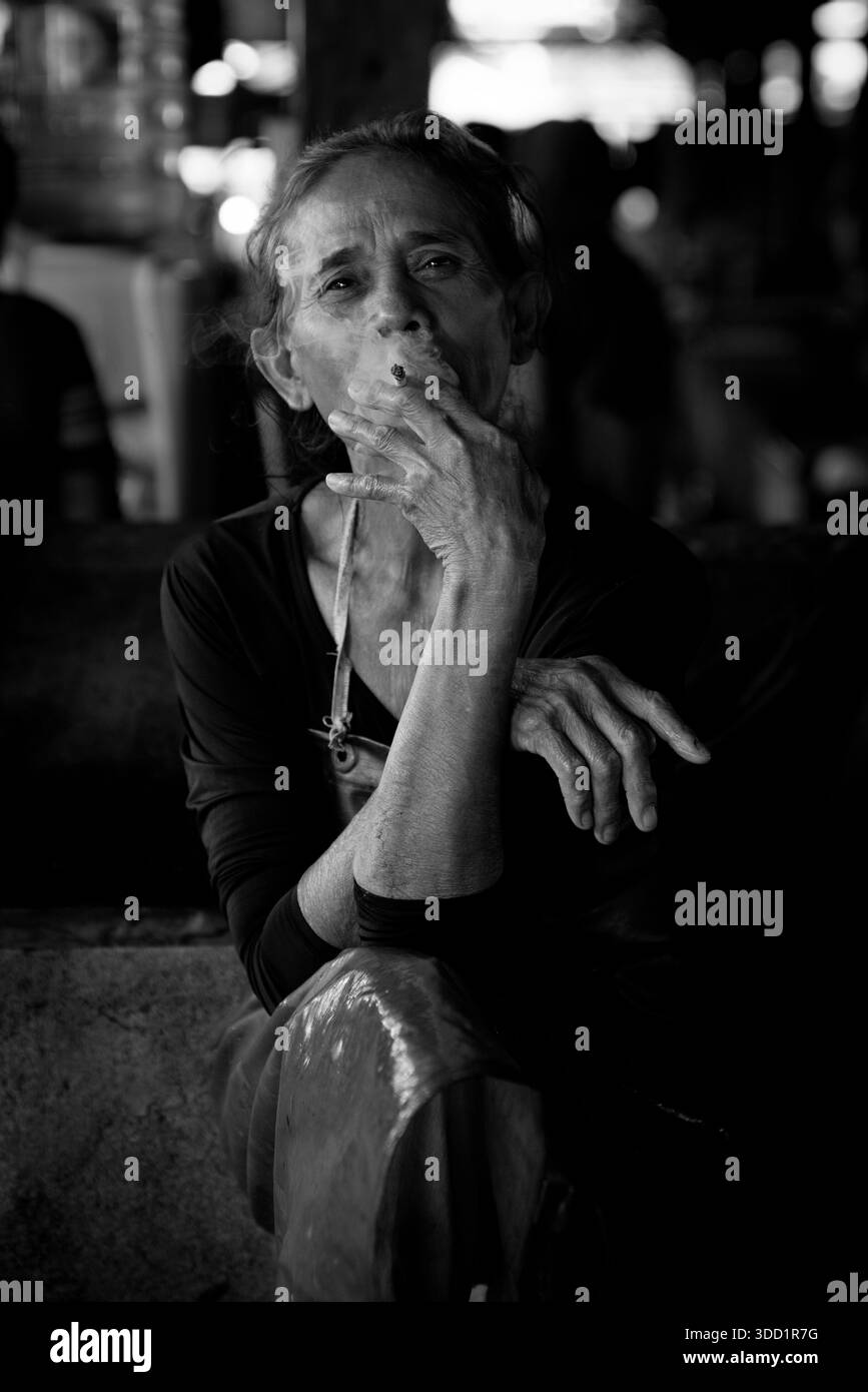 Soumful Noir et Blanc Portrait d'une femme âgée fumant une cigarette en basse lumière Banque D'Images