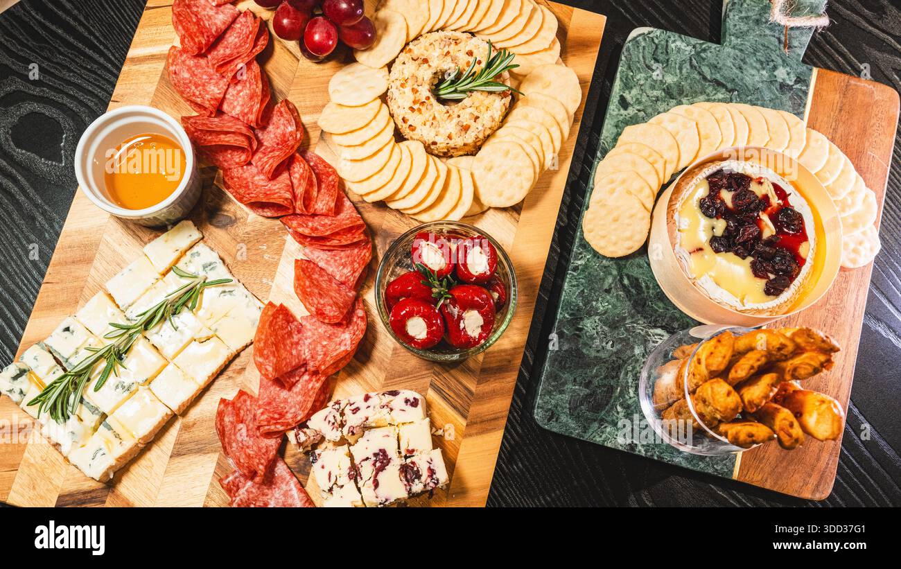 Belle planche de charcuterie avec salami, raisins, craquelins, assortiment de fromages, camembert cuit au four avec sauce aux fruits, fromage à la crème, poivrons farcis et miel Banque D'Images