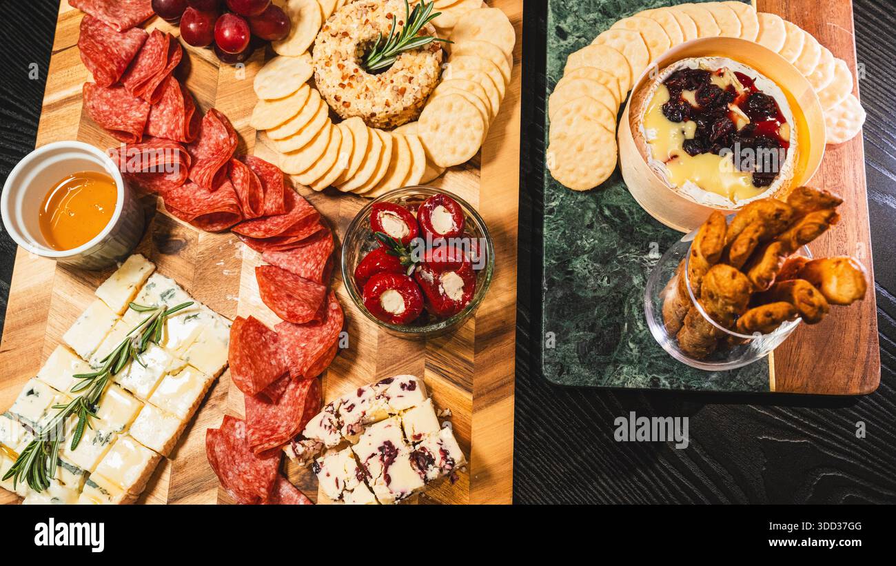 Belle planche de charcuterie avec salami, raisins, craquelins, assortiment de fromages, camembert cuit au four avec sauce aux fruits, fromage à la crème, poivrons farcis et miel Banque D'Images