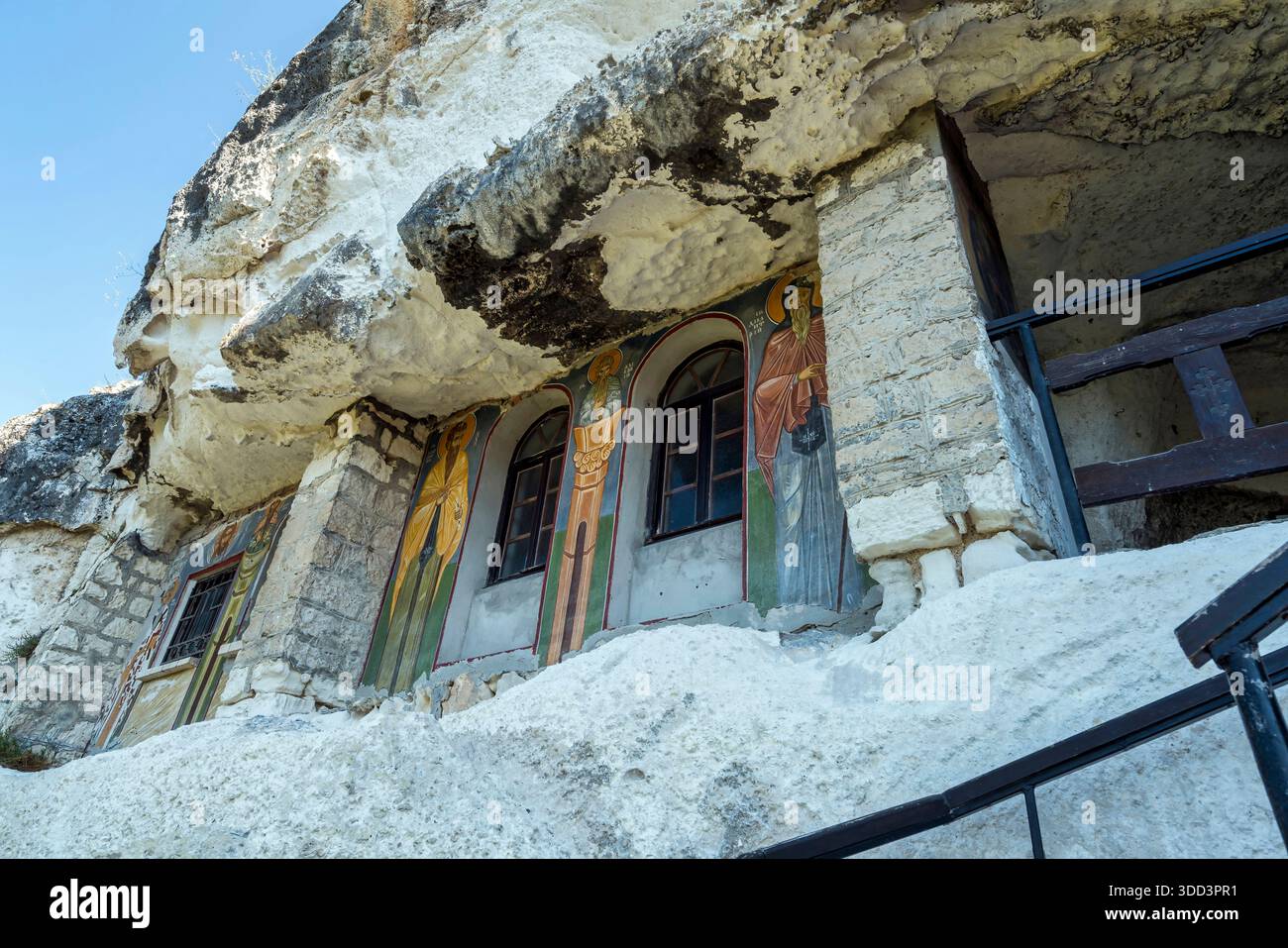 Extérieur du monastère de Basarbovo avec fresques colorées de saint peintes autour de fenêtres cintrées sculptées dans un mur de falaise de calcaire. Banque D'Images