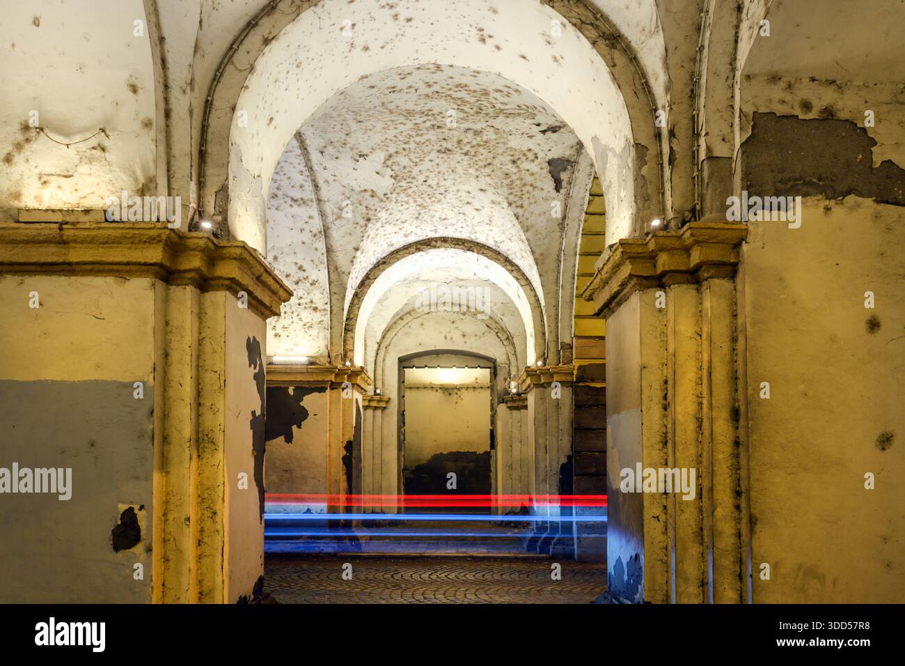 Couloir arqué usé avec peinture écaillée et traînées de lumière de voiture, longue exposition avec mise au point sélective Banque D'Images