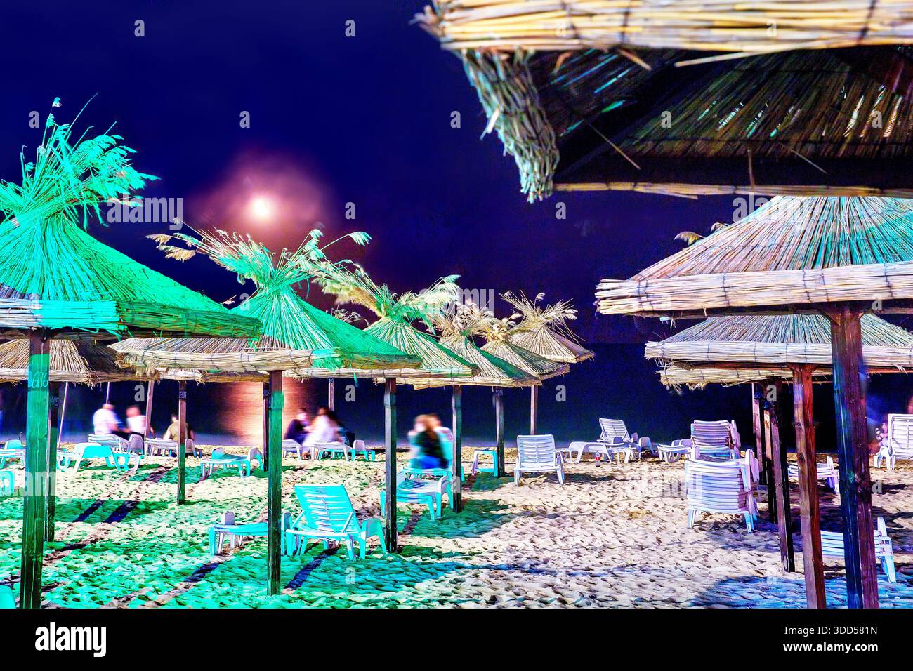 Plage la nuit avec des toits de chaume méconnaisséBle personnes - (se déplaçant à une longue exposition) Banque D'Images
