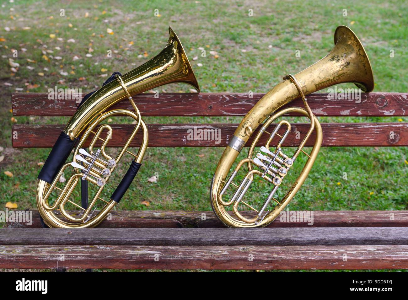 Une paire d'instruments de musique à vent, une vieille corne de ténor, appuyée contre un banc en bois dans un parc. Banque D'Images