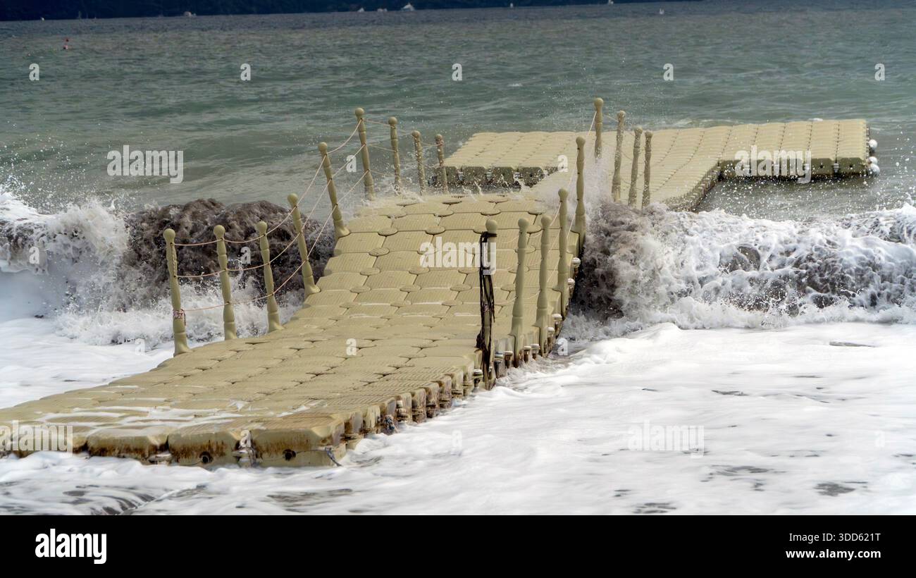 Quai flottant en plastique sur une mer ondulée avec des vagues qui s'écrasent, capturant la puissance brute de la nature et des conditions de mer turbulentes. Banque D'Images