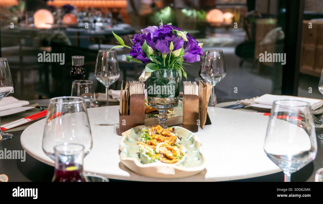 Table ronde du restaurant Lxury pour les repas de groupe avec verres à vin, fleur violette et thé turc créant une atmosphère élégante Banque D'Images