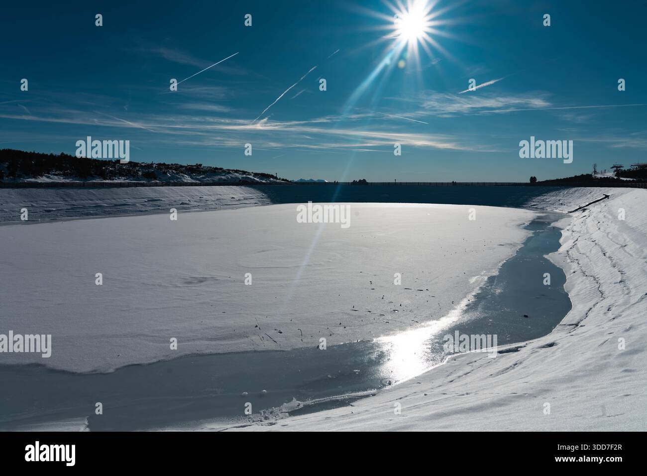 Lac artificiel gelé. Le soleil brille et fait fondre la couche de glace. Réchauffement climatique, hausse des températures et urgence climatique. Banque D'Images