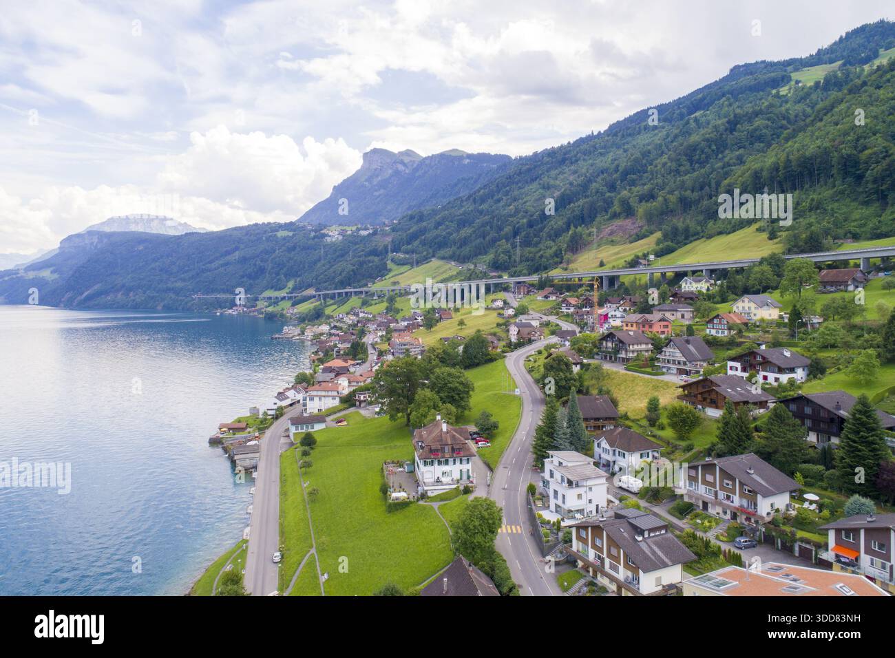 Vue aérienne d'un charmant village au bord du lac niché contre des collines verdoyantes, où les routes sinueuses rencontrent les eaux tranquilles sous un vaste ciel, Treptower par Banque D'Images