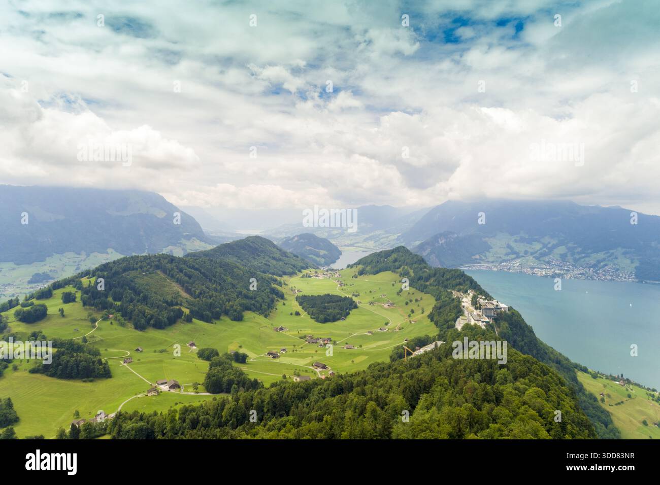 Vue aérienne des collines verdoyantes rencontrant les eaux bleues sereines d'un lac, avec des montagnes lointaines sous un ciel nuageux, Treptower Park, Berlin, allemand Banque D'Images