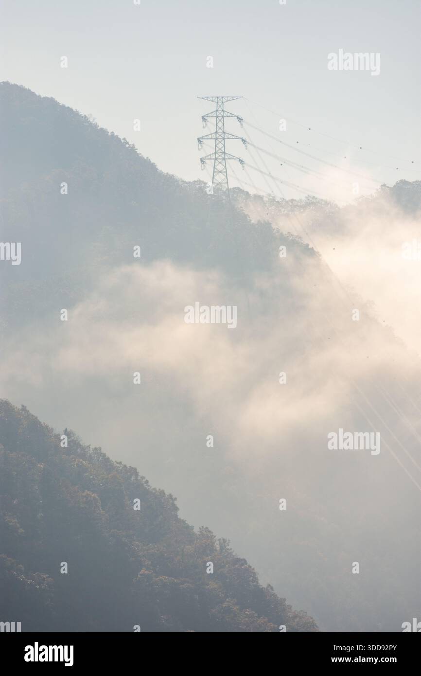 Paysage de montagne brumeux avec une tour de ligne électrique. Banque D'Images