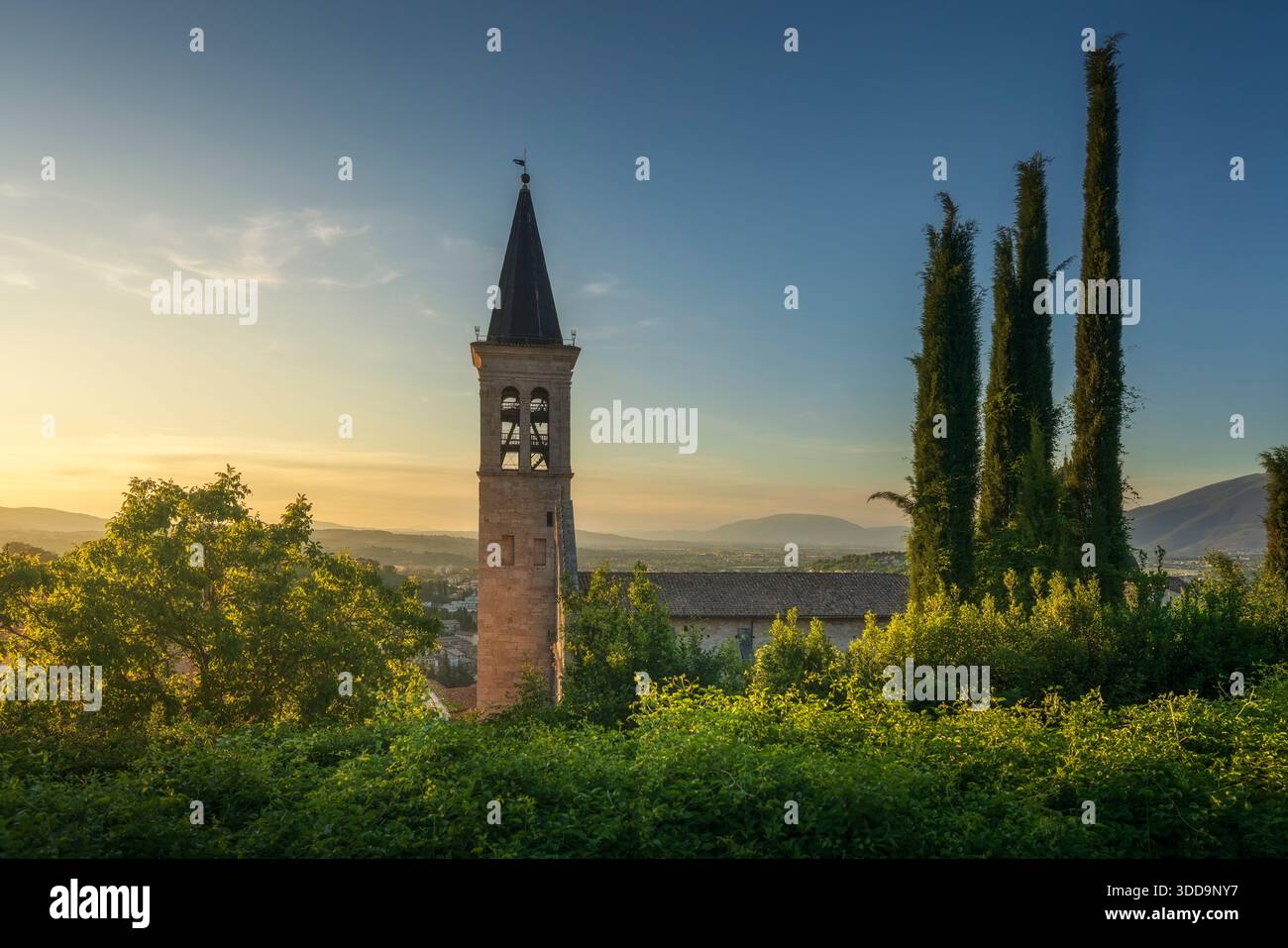 Une vue latérale du clocher de la cathédrale de Spoleto au coucher du soleil. La cathédrale Santa Maria Assunta avec des cyprès et une vue panoramique sur la région de l'Ombrie, Banque D'Images