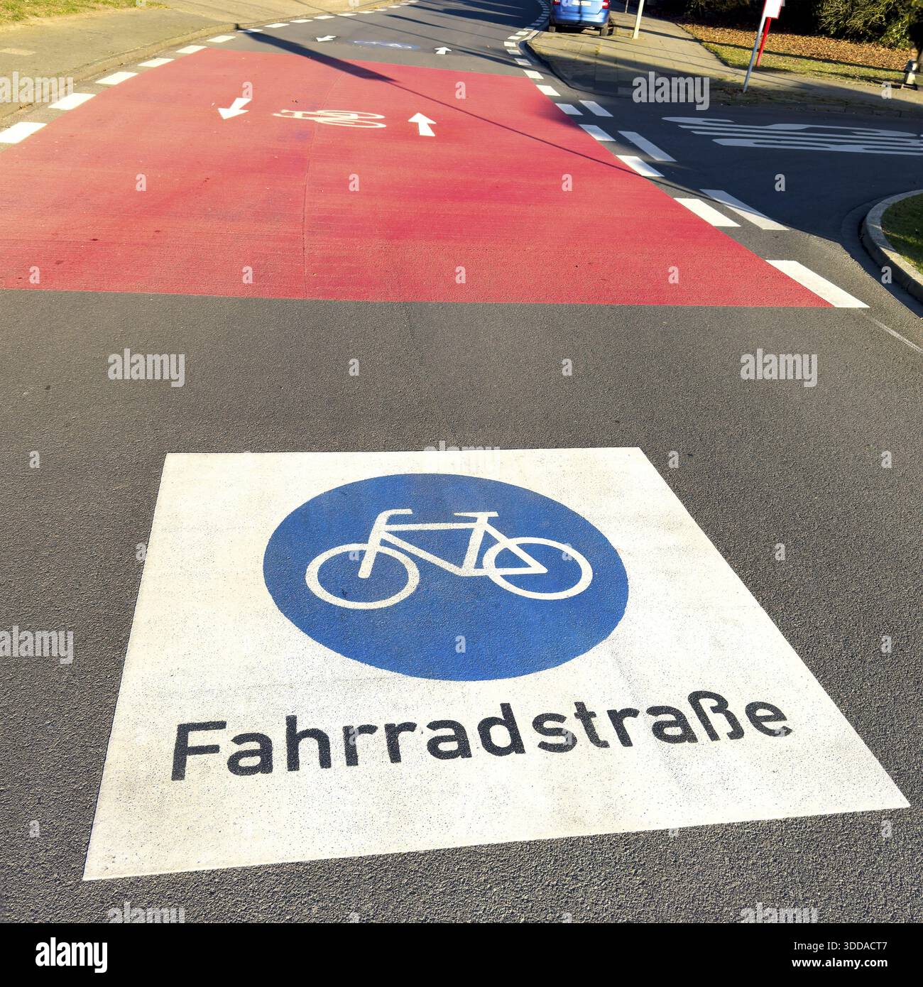 Grand marquage sur la route peint symbole pour les panneaux de signalisation routière 244.1-40 début fin d'une route cyclable, derrière elle rouge intersection route confluence, Allemagne Banque D'Images